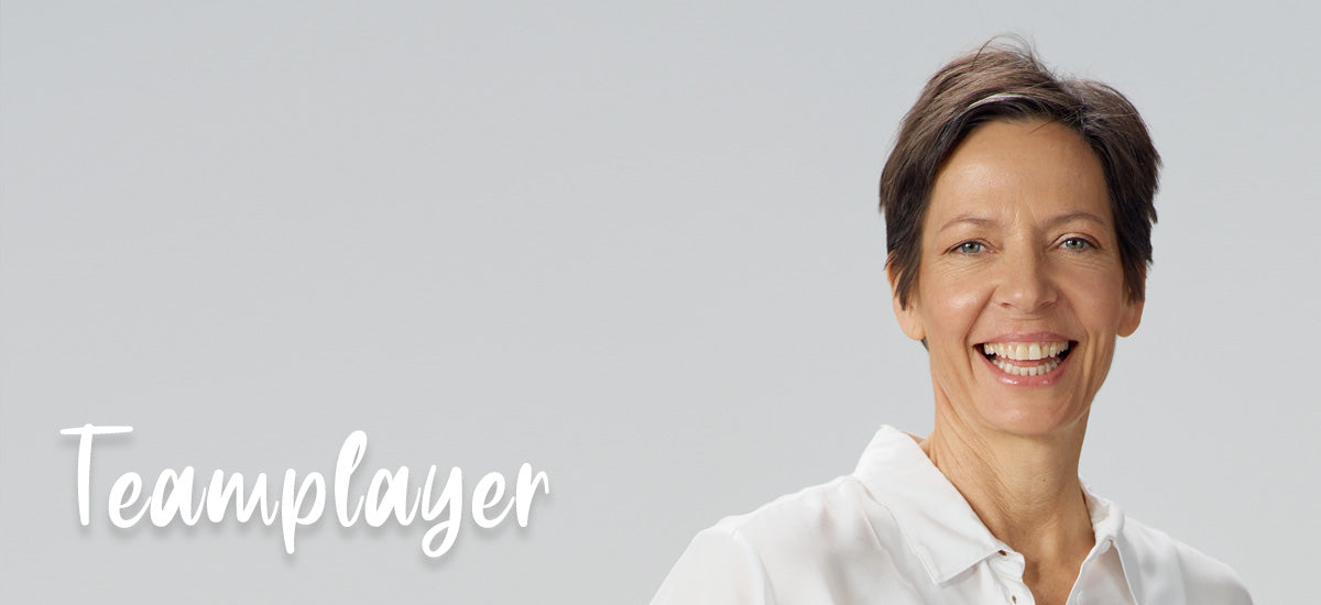 Frau lacht in die Kamera, daneben steht das Wort Teamplayer